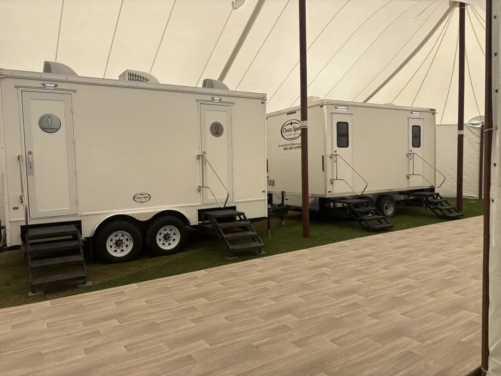 Clean Spot luxury restroom trailer set up beside an event tent on the water