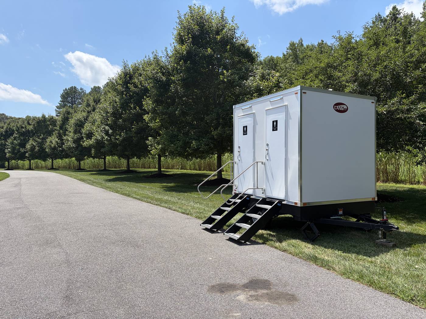 Two station restroom trailer set up along a tree lined drive at a private estate